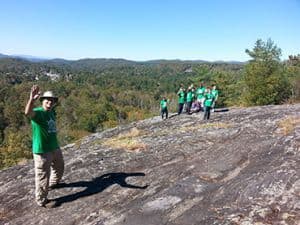 Students hiking outdoors at Pensacola State College with scenic landscape background.