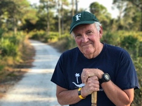 Senior man holding a walking stick, outdoors, discussing books for Floridians at Amos Studio.