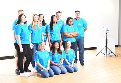 Diverse group of Pensacola State student ambassadors in matching blue shirts posing for a photo.