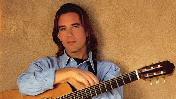 Guitarist playing fingerstyle acoustic guitar at Pensacola State College event.