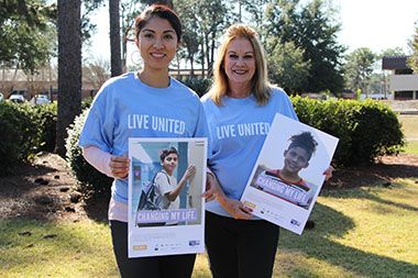 Two women holding United Way campaign posters outdoors.