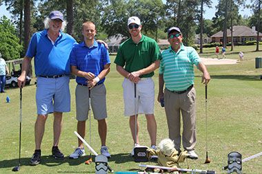 Four men posing with golf clubs at Pensacola State&rsquo;s annual Big Break Golf Classic.
