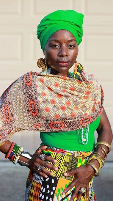 African performer in colorful traditional dress for 'Up From The Mud' presentation.