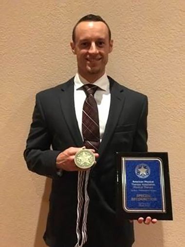 Student with medal and plaque celebrating academic achievement at Pensacola State College.