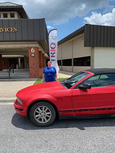 Student Support Services TRIO participant at Pensacola State College with red car.