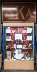 Delta Kappa Alpha fraternity memorial cabinet showcasing awards and memorabilia.