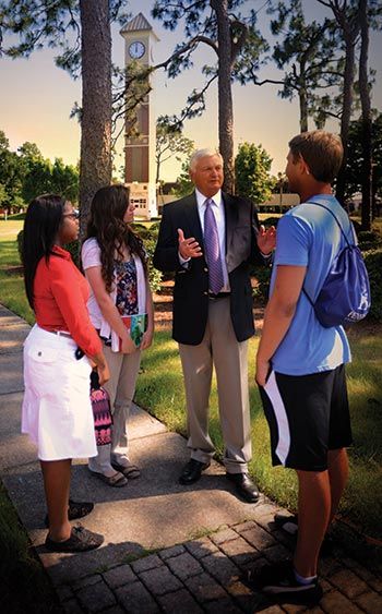 Pensacola State College students discuss financial benefits with an administrator outdoors.