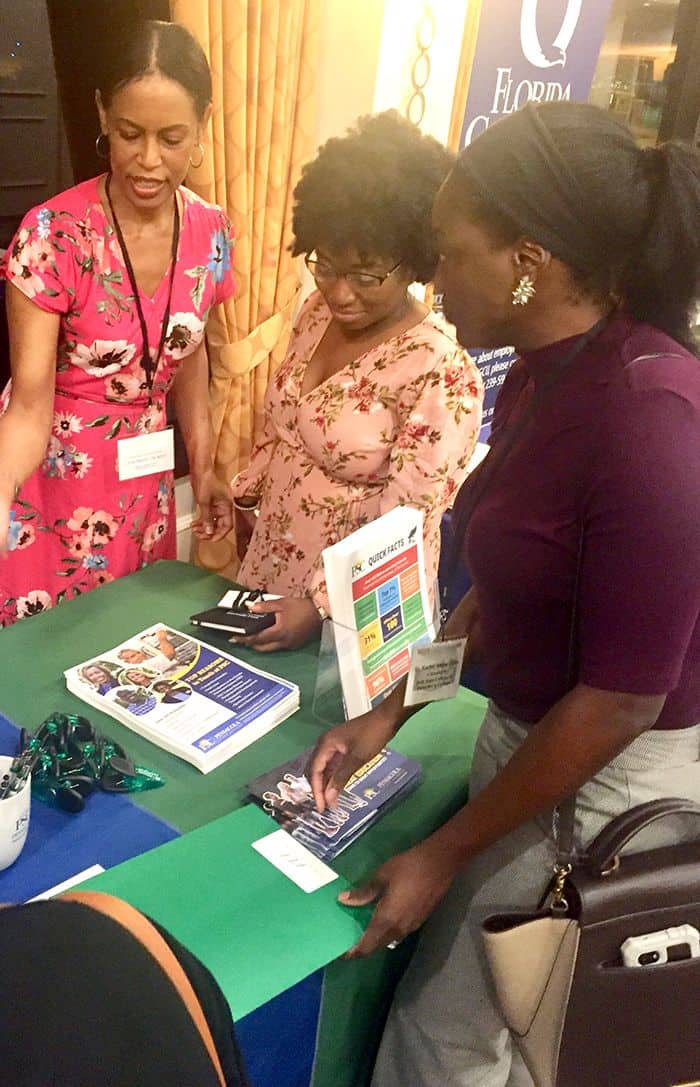 Diverse women discussing college programs at Pensacola State College booth in Tampa.