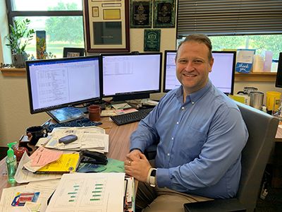 Institutional Research Director Michael Johnston working at his desk with multiple monitors and data.