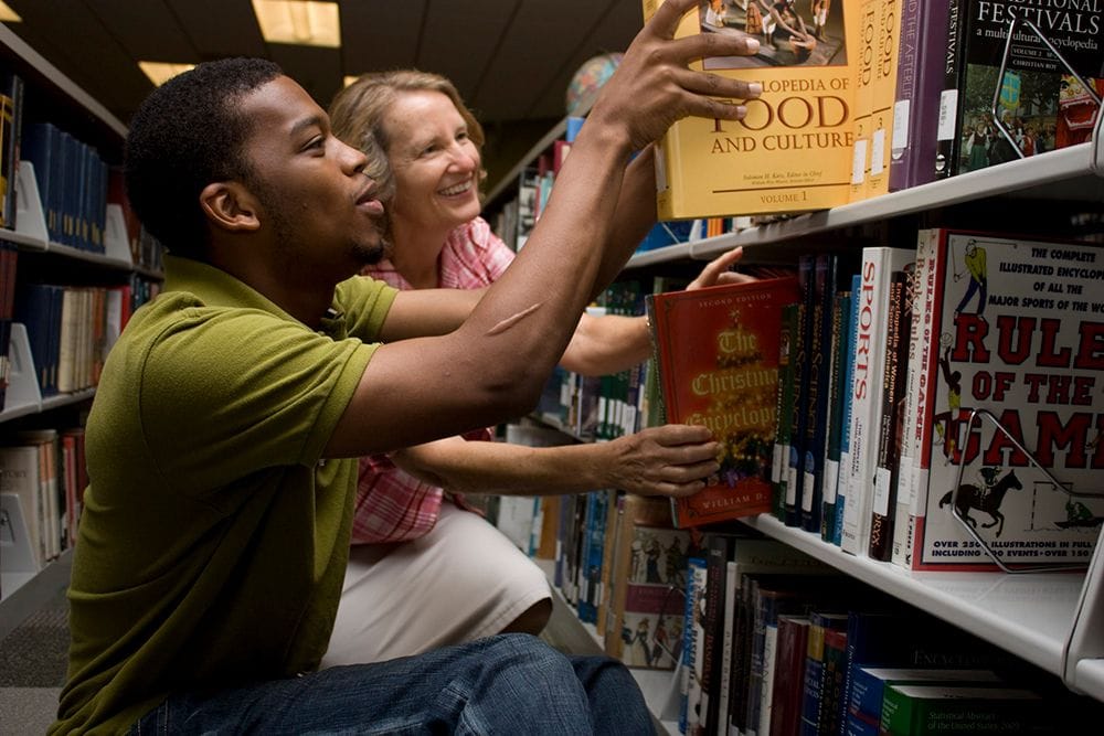 Students exploring academic resources in a college library for higher education.