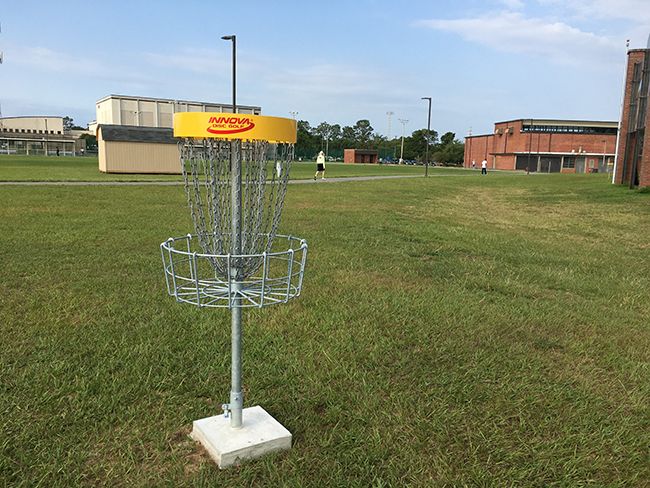Disc golf basket on the Pensacola State College campus, promoting outdoor recreation and student eng.