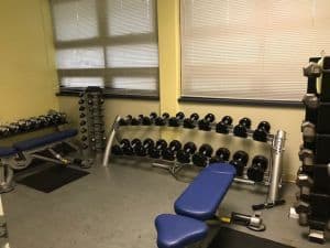 State-of-the-art fitness equipment including dumbbells and benches at Pensacola State College gym.