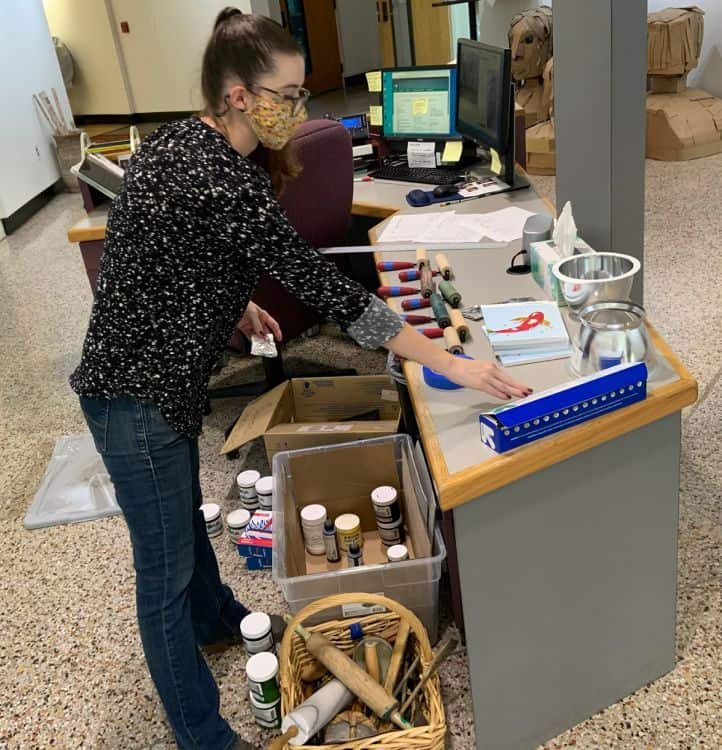 Visual arts instructor organizing supplies for hurricane readiness in classroom.