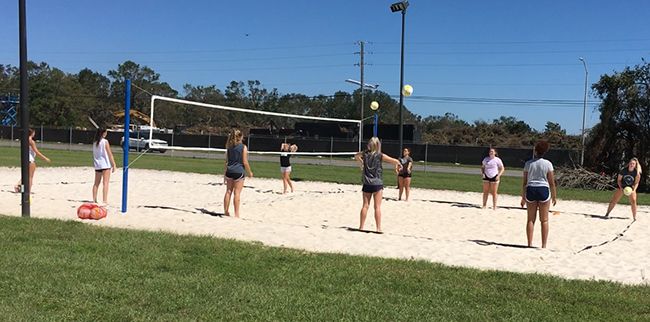 Students practicing beach volleyball outdoors at Pensacola State College campus.