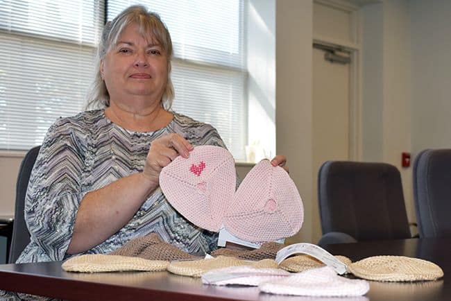 Woman holding handmade breast prostheses for breast cancer survivors at PSC Stitchin&rsquo; to Serve.