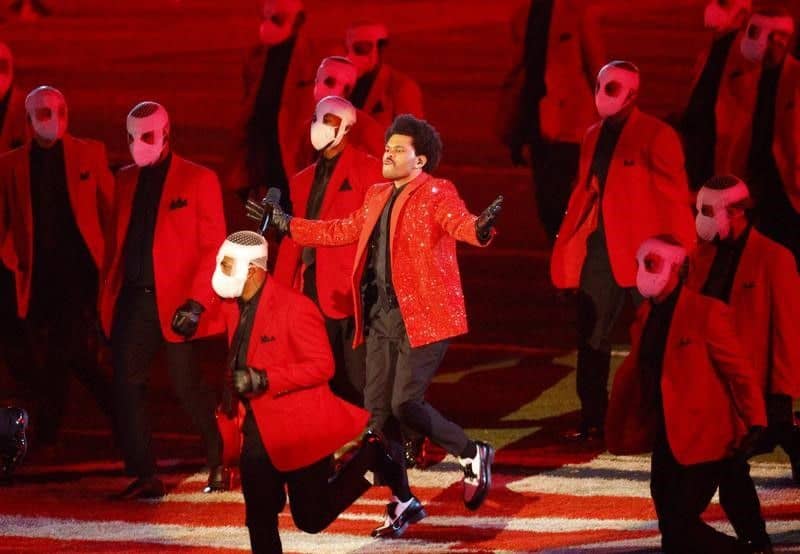 Music performer in red jacket with backup dancers in red suits and masks during Super Bowl LV halfti.