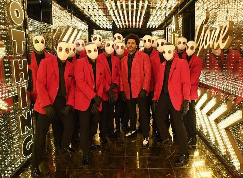 Performers in red suits with white masks at Super Bowl LV halftime show, Pensacola State College eve.