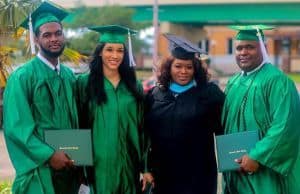 Diverse group of graduates in green caps and gowns with family at Pensacola State College graduation.