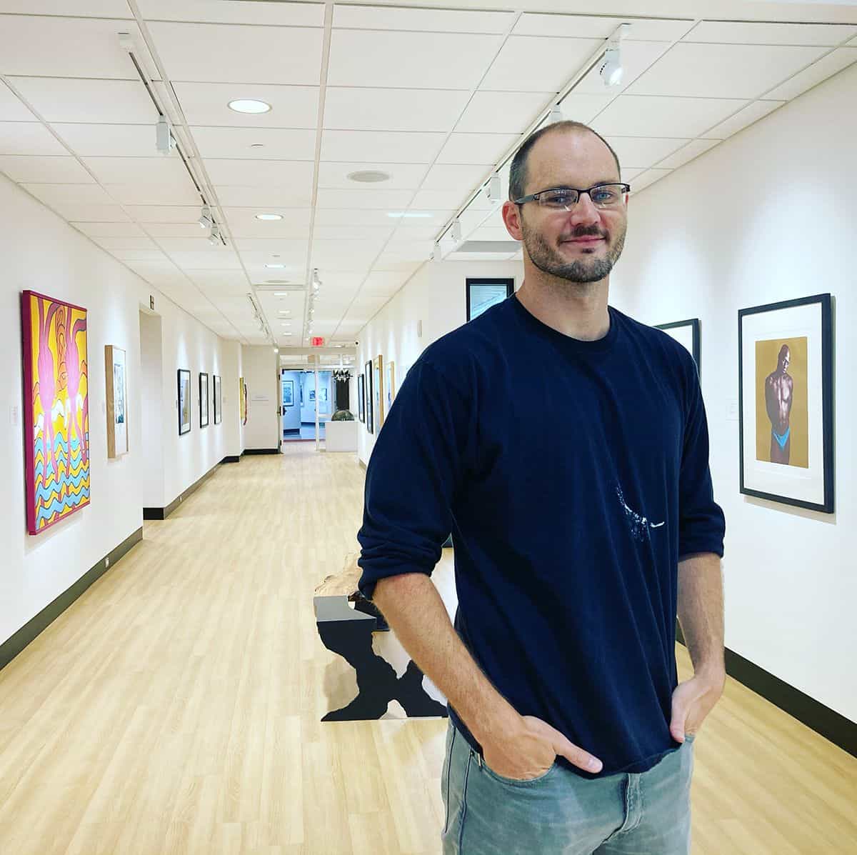 Art gallery director at Pensacola State College showcasing artwork in a modern gallery space.