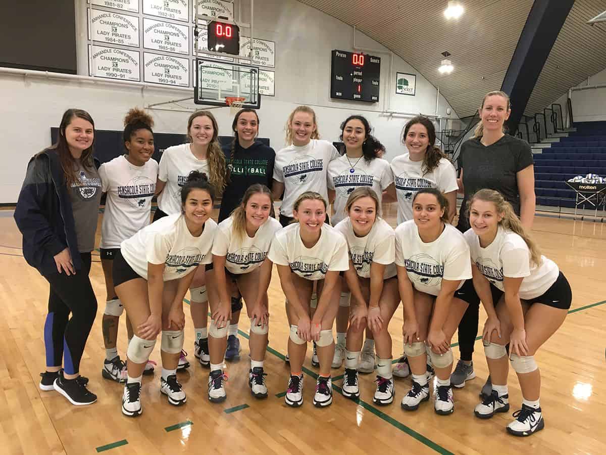 High school volleyball team posing on the court after making playoffs under new coach.