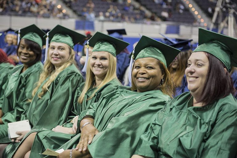 Graduates in green caps and gowns at Pensacola State College graduation.