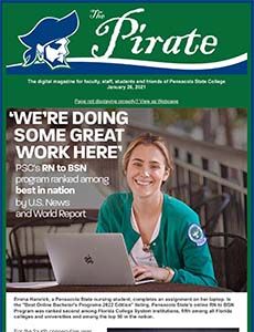 Pirate student smiling while working on a laptop at college campus.