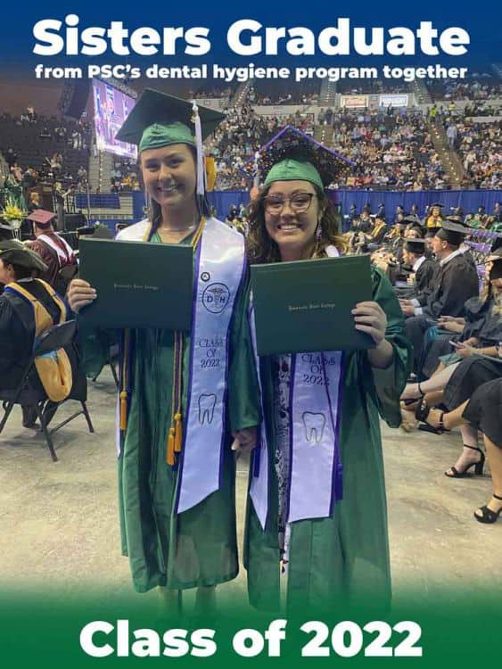 Graduates in green caps and gowns holding diplomas at graduation ceremony.