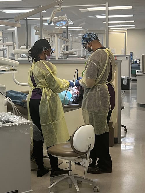 Dental hygiene students practicing clinical skills in a modern dental lab setting.