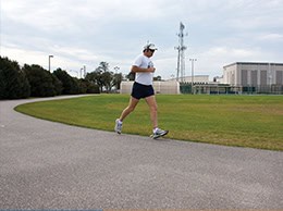 Student jogging outdoors on campus walking path for fitness and health improvement.