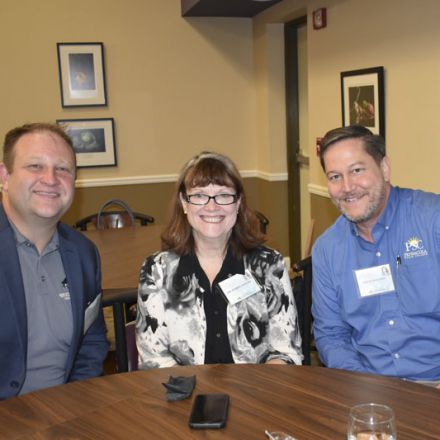 High school counselor and college representatives celebrating scholarship milestone.