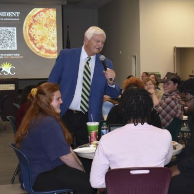 Engaging college event with the president, students, and pizza, promoting community and higher educa.