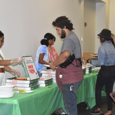 Students and staff enjoy pizza together during a college event promoting community and campus involv.