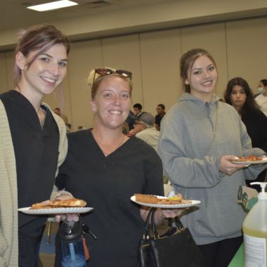 Diverse students and staff enjoy pizza together during the college's community-building event.