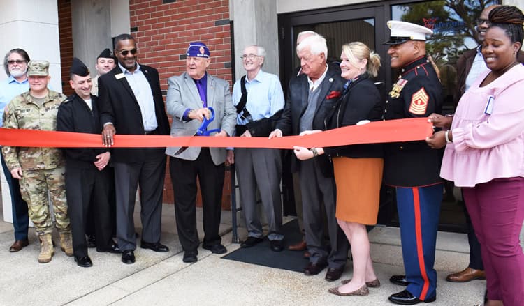 Group of diverse veterans and officials at Pensacola State College ribbon-cutting ceremony.