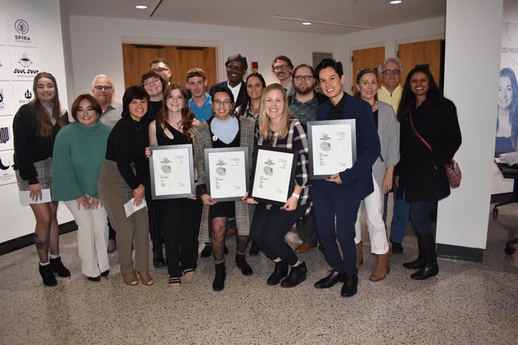 Diverse group of students and faculty celebrating at the Pensacola State College Graphic Design Seni.