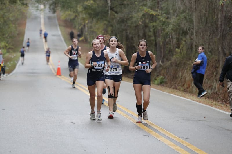PSC Cross Country team running on a rural road during a race.