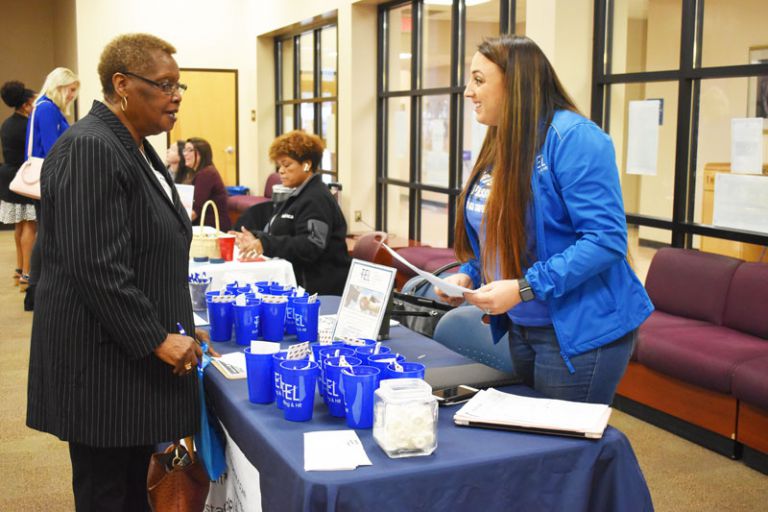 Diverse student engaging with college representative at job fair.
