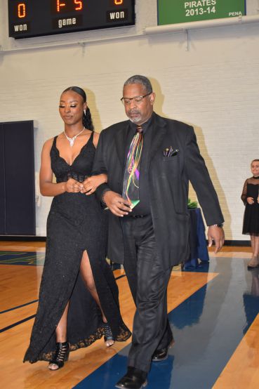 Elegant African American woman in black gown and man in suit at PSC Homecoming event.