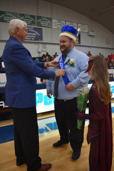 Student receives Homecoming King crown during college event.