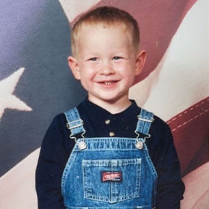 Young boy smiling in front of American flag at Pensacola State College event.