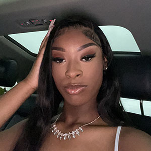 College student with long dark hair in a car, looking at the camera.