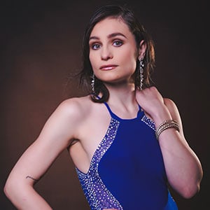 Portrait of a woman wearing a blue dress with sparkling embellishments, showcasing confidence and st.