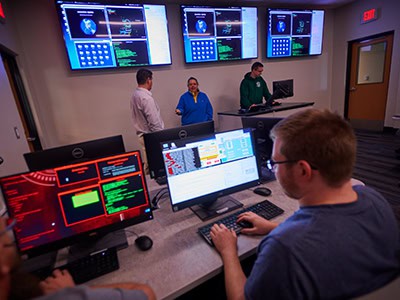 Cybersecurity students at Pensacola State College monitor security systems in a high-tech lab.