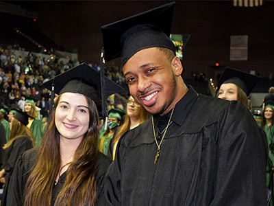 Celebrating graduation at Pensacola State College with diverse students in caps and gowns.