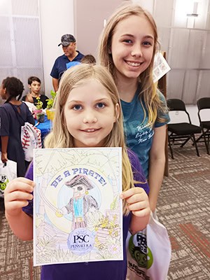 Summer camp children showcasing artwork at Pensacola State College Kids College event.