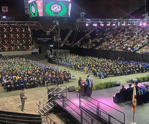 Pensacola State College spring graduation ceremony with graduates in caps and gowns at the arena.