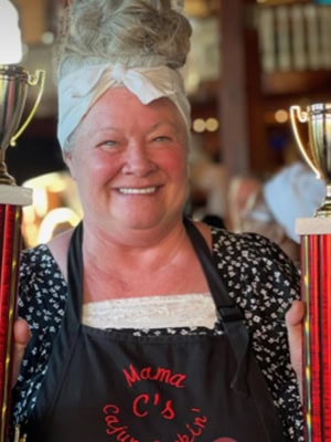 Culinary management graduate proudly holding trophies at Pensacola Gumbo Cookoff.