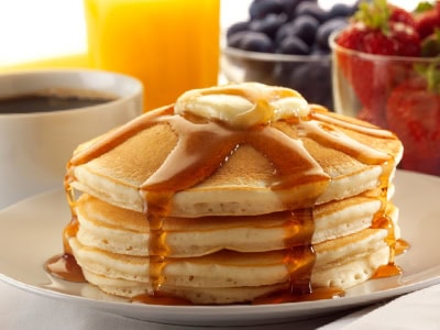 Delicious stack of pancakes topped with syrup, served with fresh berries and a cup of coffee during.