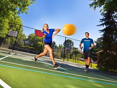 Students playing tennis and pickleball outdoors at Pensacola State College sports courts.