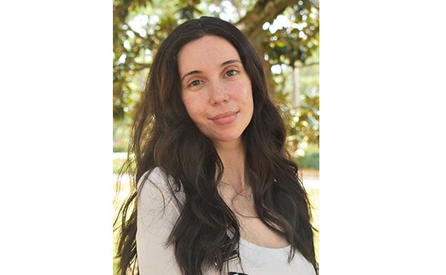 Young woman with long dark hair outdoors, celebrating 2023 Coca-Cola Leaders of Promise Scholarship.